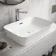 Waschbecken von Ideal Standard, rechteckig mit glatter Oberfläche, montiert auf einem weißen Möbelstück, mit einem chromfarbenen Wasserhahn im modernen Badezimmer.